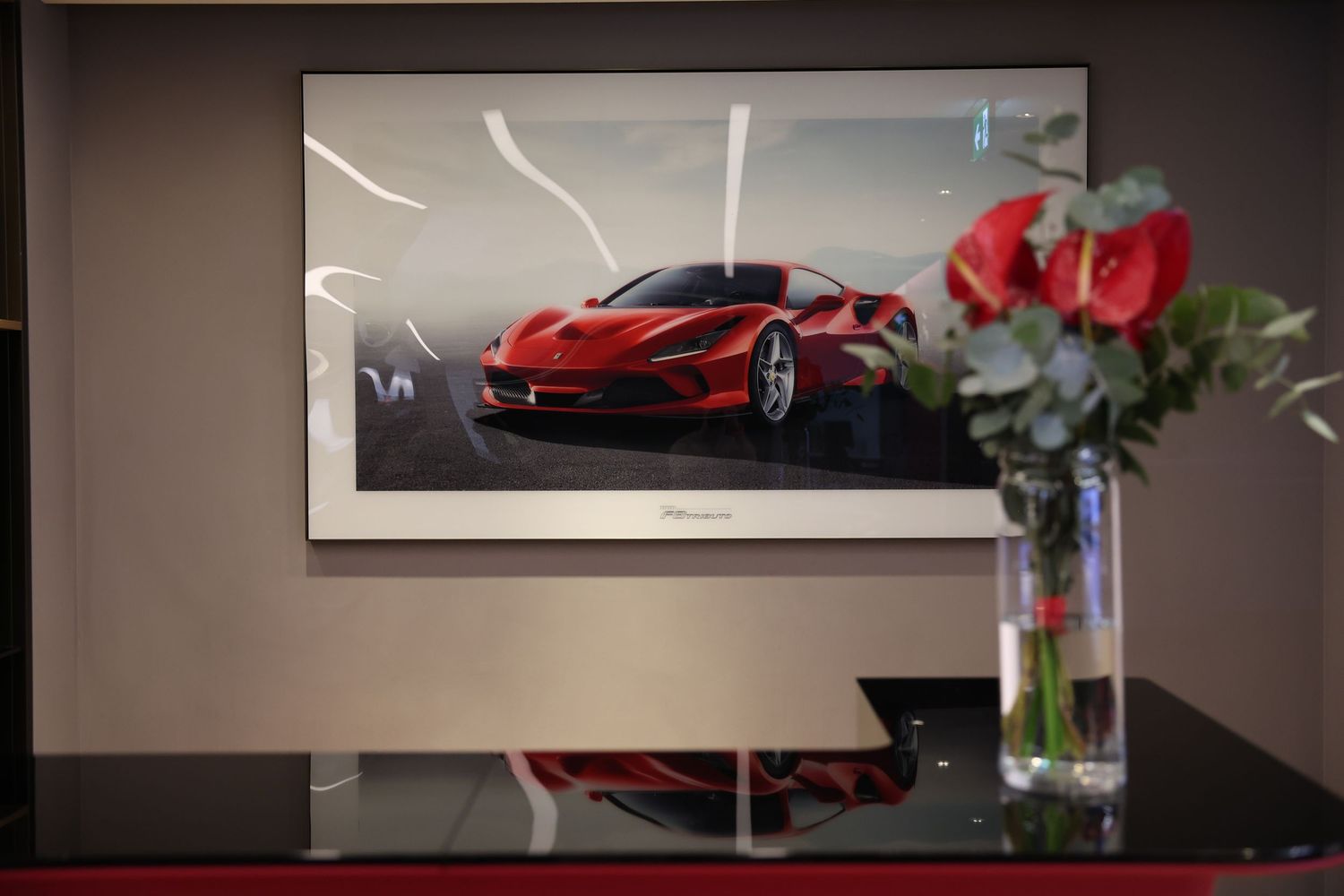 Red sports car displayed in an elegant showroom with dramatic lighting and reflective surfaces.