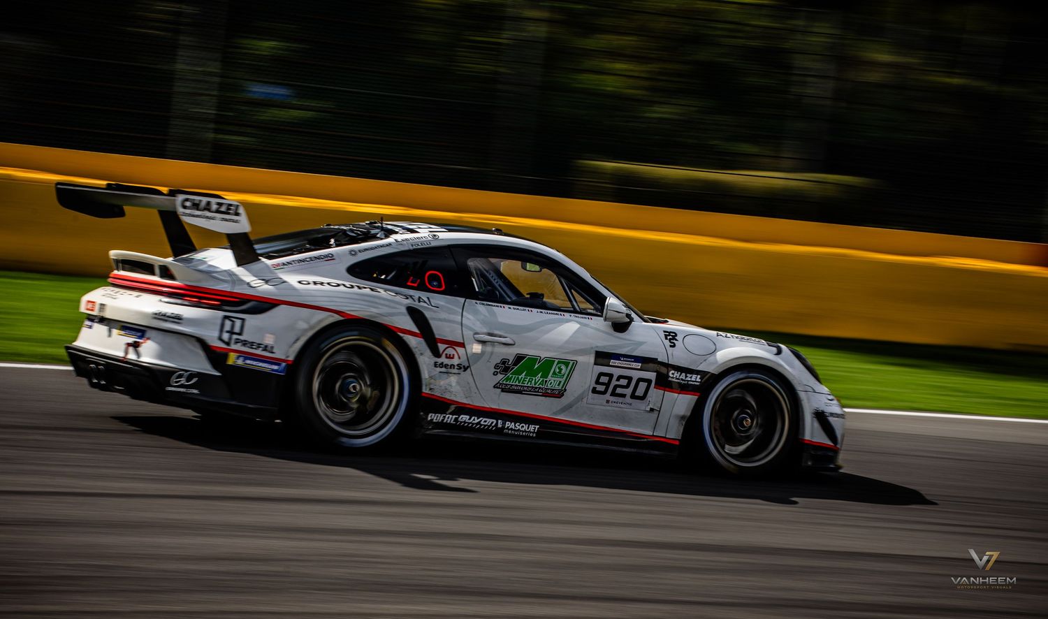 White Porsche 911 GT3 Cup race car number 920 speeding on track at a motorsport circuit event.