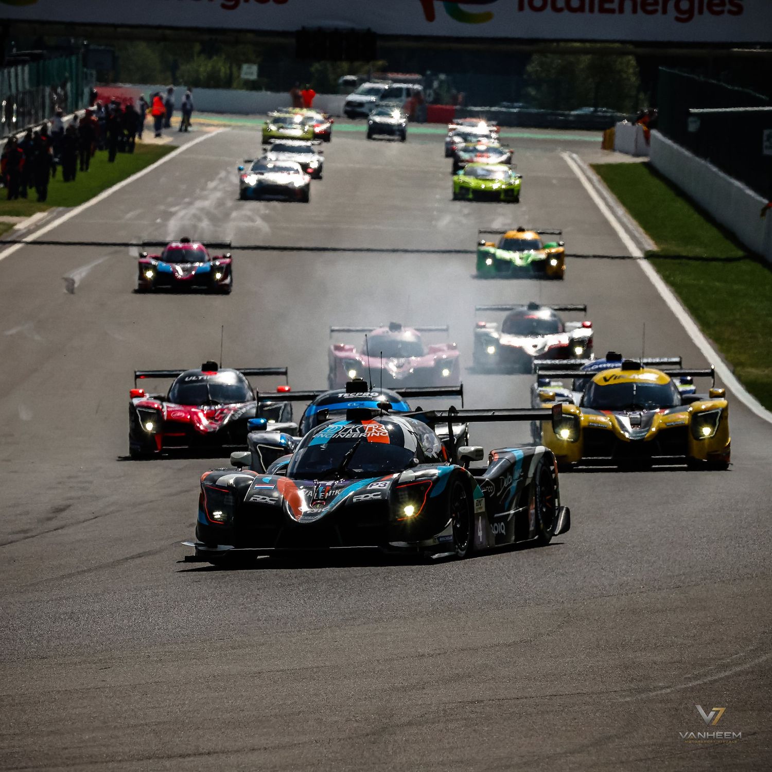 Multiple LMP racing cars compete on a circuit track during a WEC endurance race, with TotalEnergies branding visible.