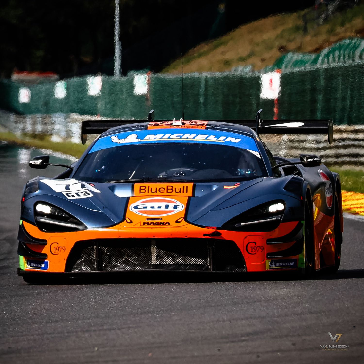 McLaren GT3 race car with BlueBull and Michelin sponsorship livery competing on a racing circuit.