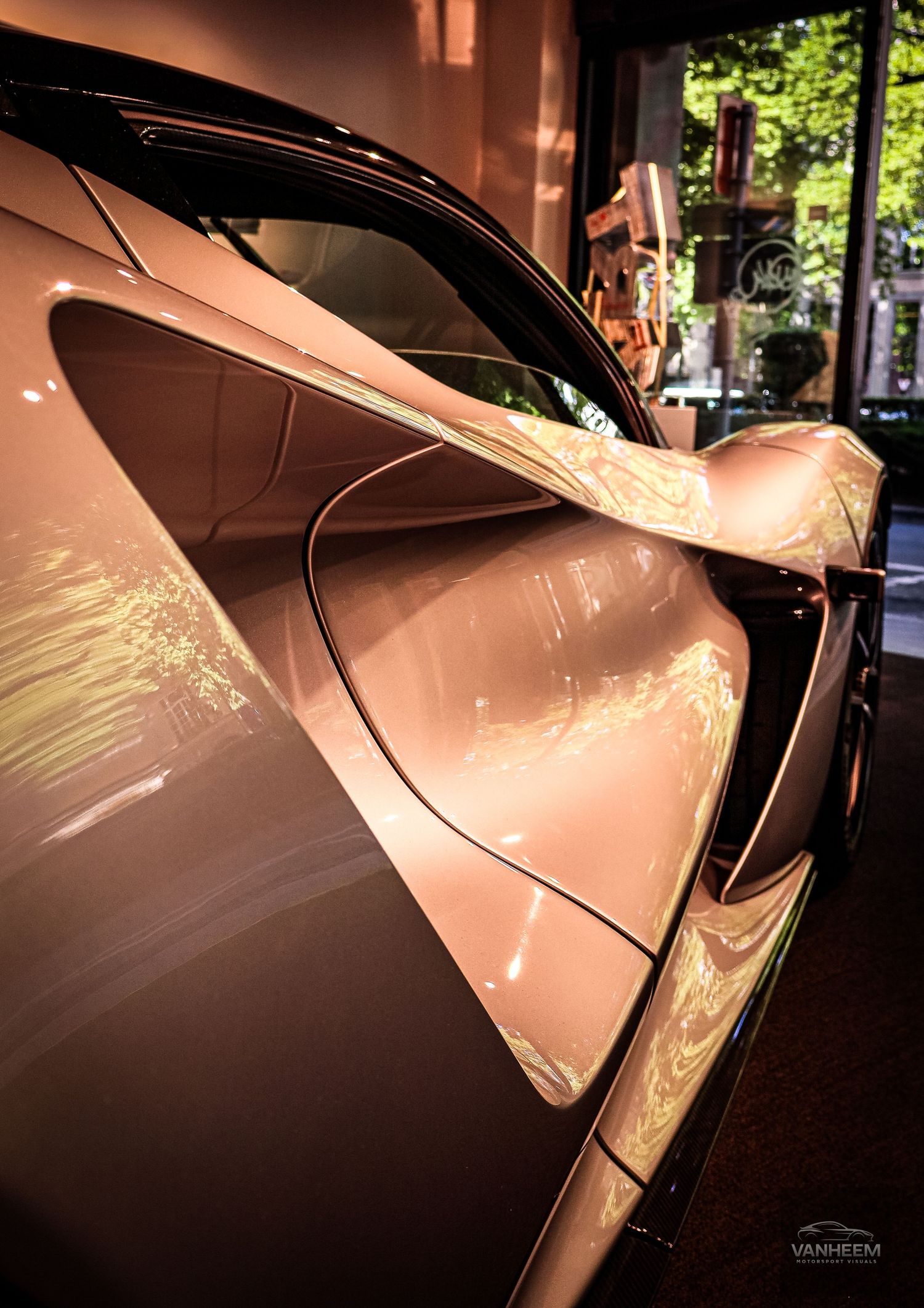 Close-up of a sleek rose gold luxury sports car with reflective bodywork displayed in a showroom.