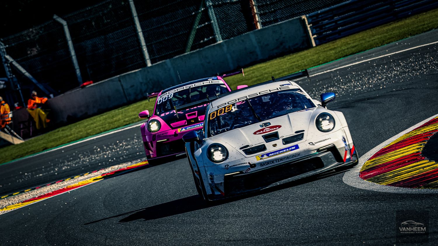 Racing cars competing on a professional circuit during daytime competition.