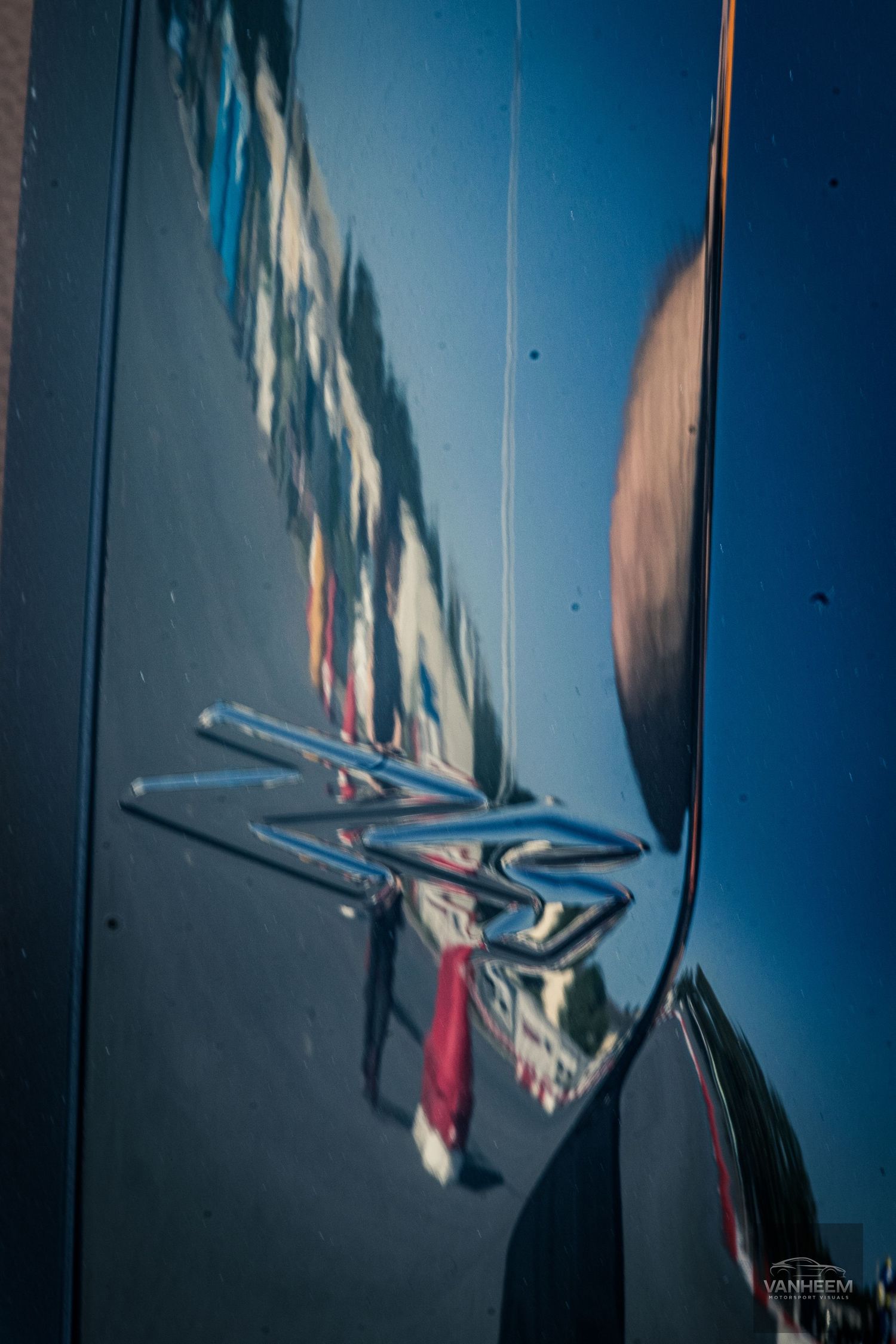 Abstract artistic photograph showing distorted reflections in a metallic surface against a deep blue sky background.