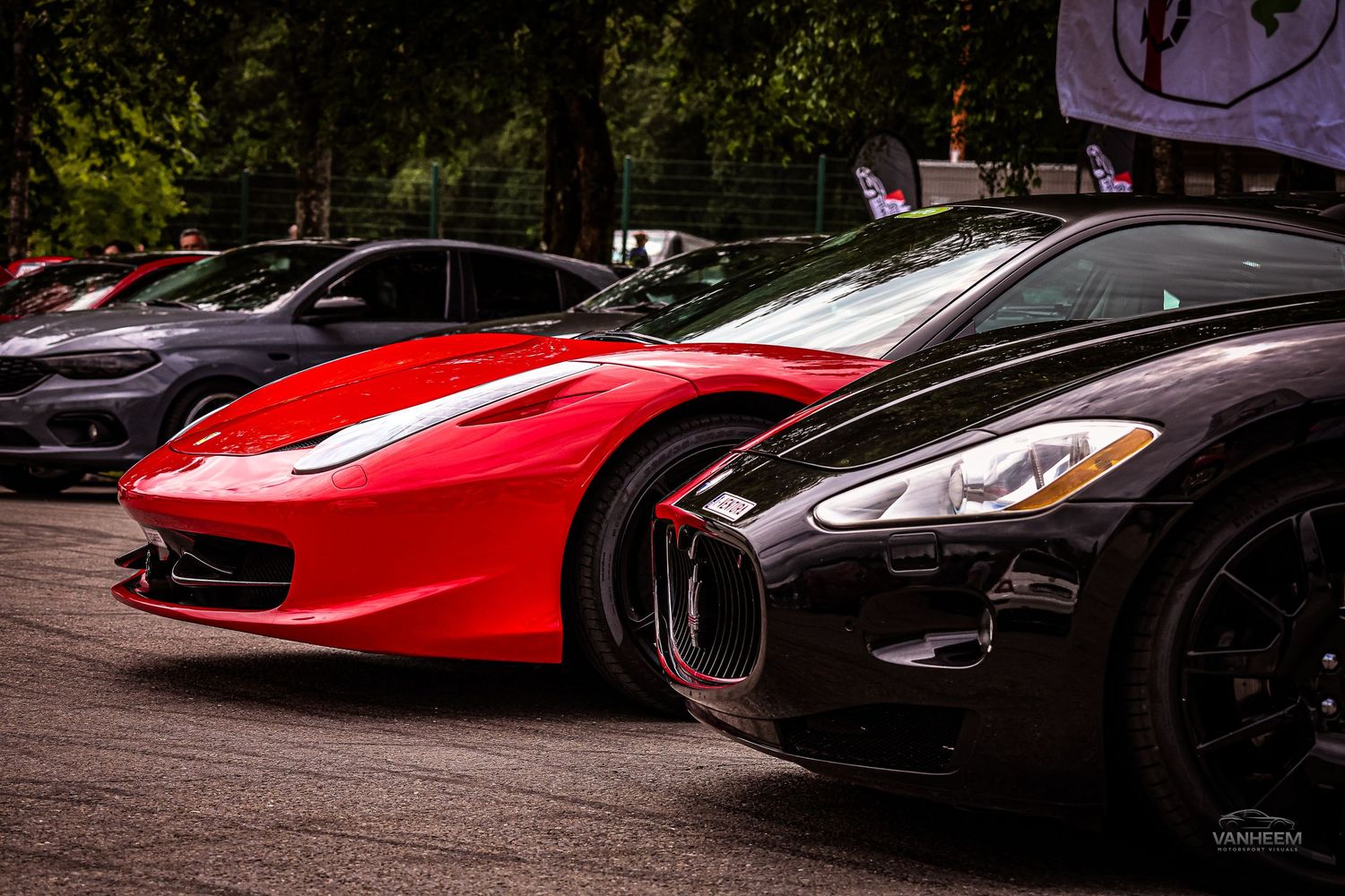 Red Ferrari and black Maserati GranTurismo parked side by side at an exotic car meet outdoors.
