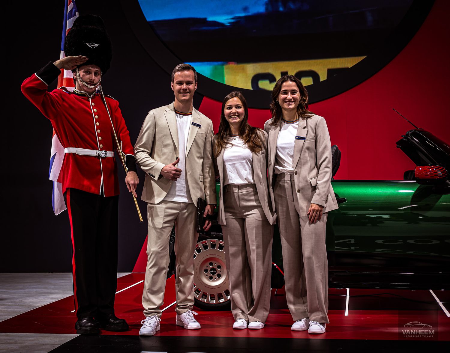 Auto show presentation stage with red lighting and ceremonial guards in traditional uniforms.
