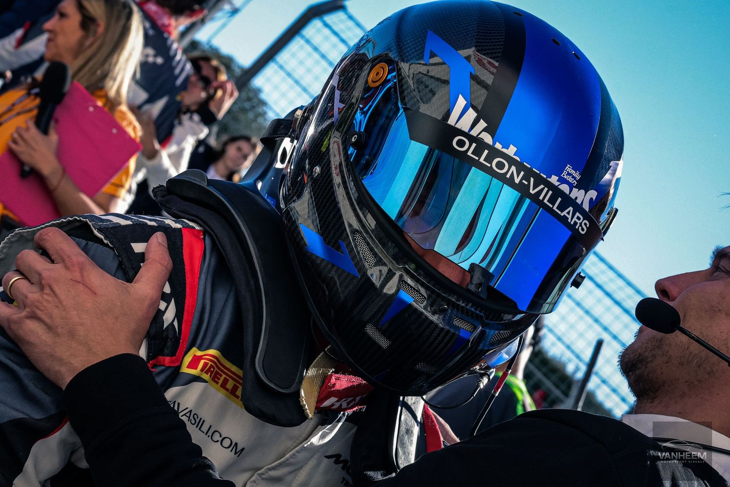 A person wearing a blue reflective motorcycle helmet looking to the side against a bright background.