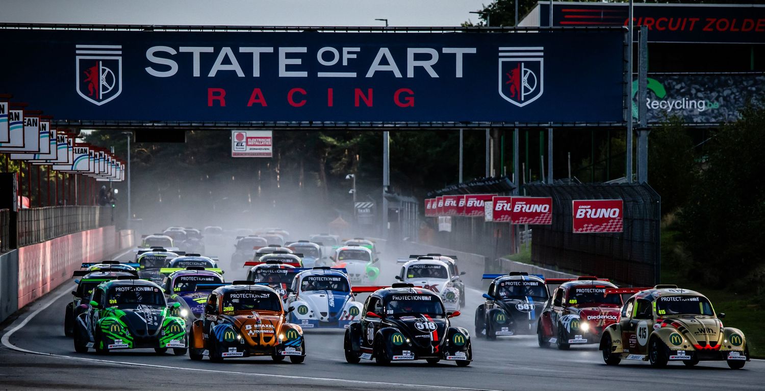 Multiple colorful racing cars compete at the start of a wet State of Art Racing circuit race event.