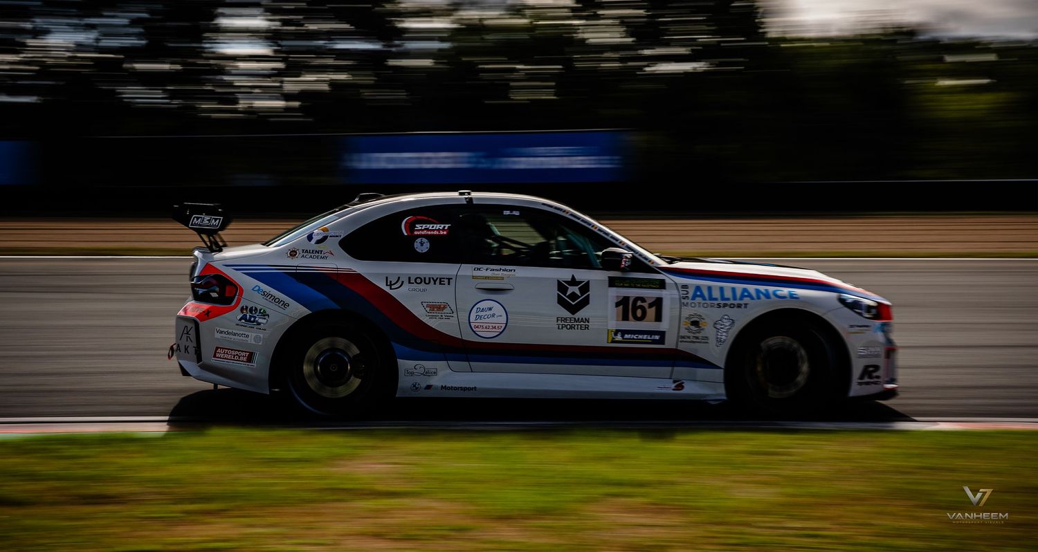 BMW M2 race car number 161 with sponsor livery speeding on a racing circuit track during a motorsport competition.