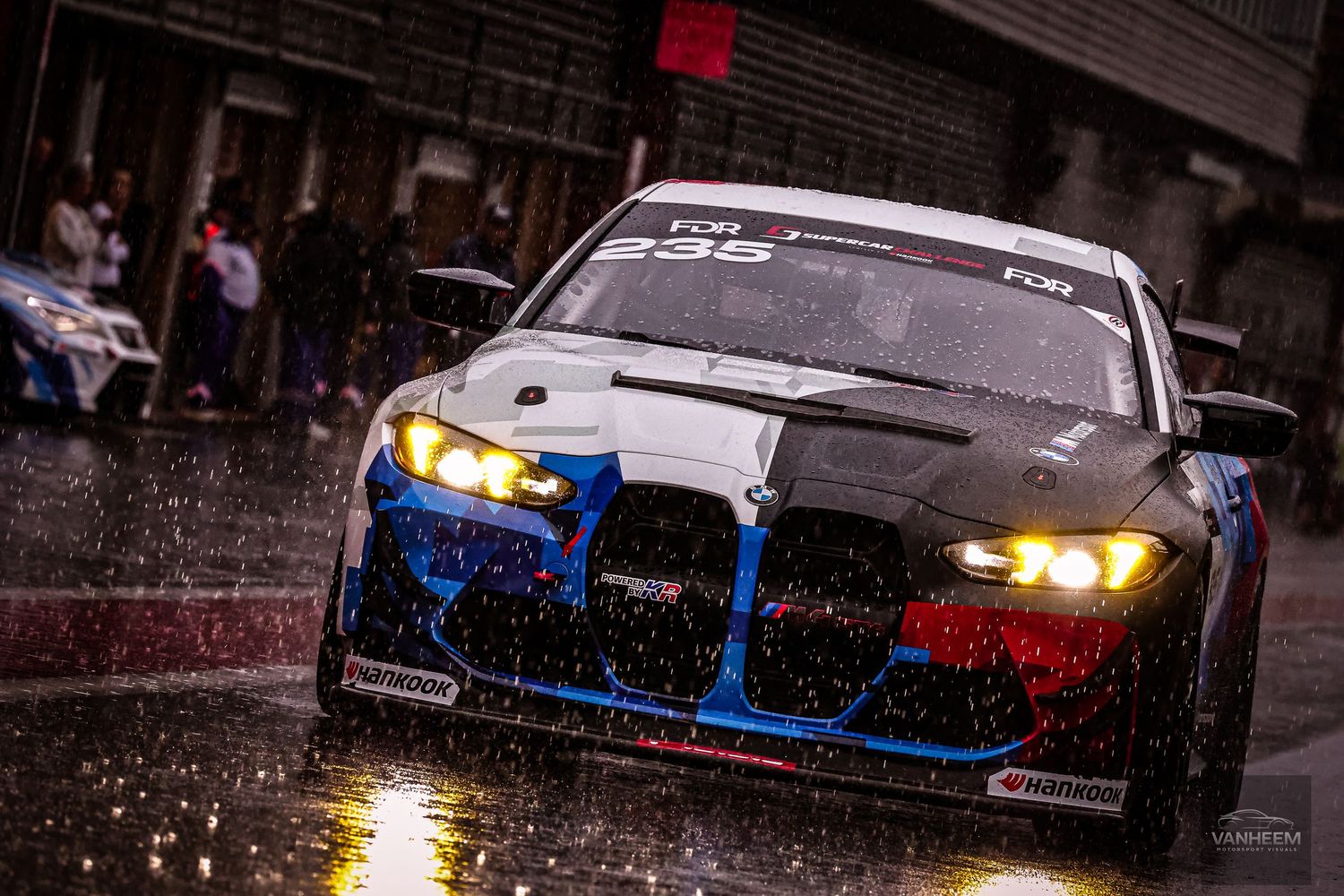 BMW M4 GT3 race car number 335 racing in heavy rain on a wet track during a motorsport endurance event.