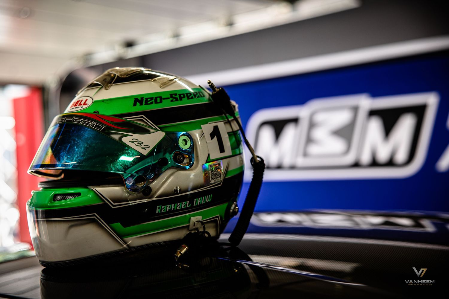 Green and chrome racing helmet with Neo-Split branding displayed on a shelf in front of M3M signage.