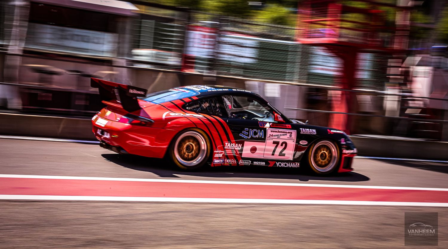 Red #72 race car speeding on track, motion blur background, motorsport competition photography.