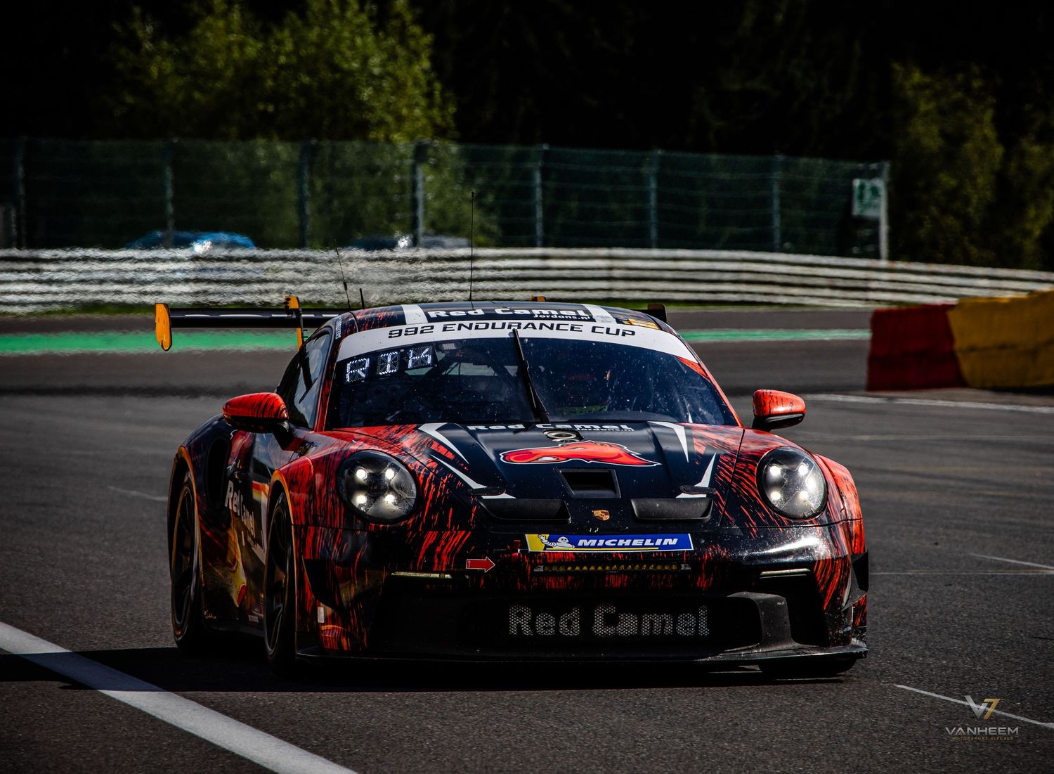 Red Camel Porsche 911 GT3 race car with aggressive livery competing on Spa-Francorchamps circuit.
