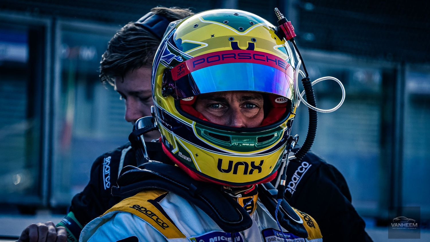 Close-up of colorful racing helmets lined up in a row during a motorsport event.