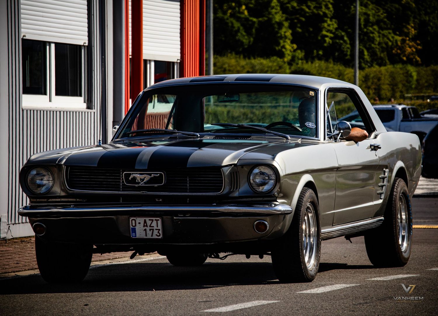 Classic black and white Ford Mustang with racing stripes parked on a street, showcasing vintage 1960s American muscle car design.