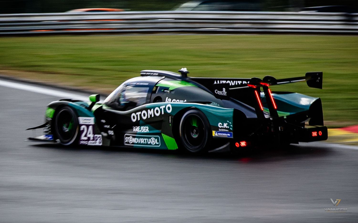 Green and black OTOMOTO #24 LMP racing car speeding on a wet track during an endurance race.