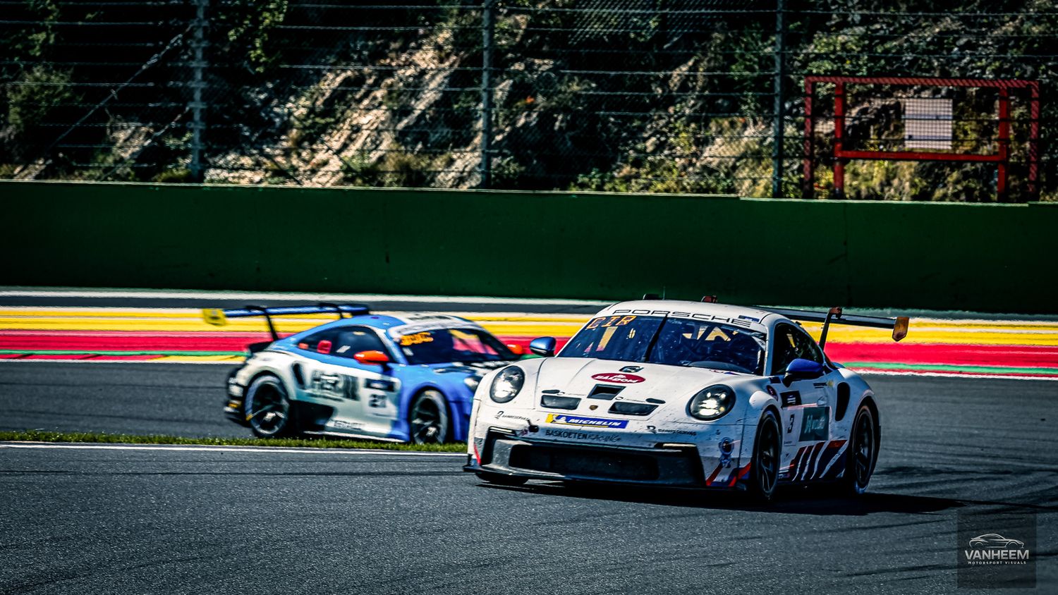 Racing cars speed around a track during a competitive motorsport event at a professional racing circuit.