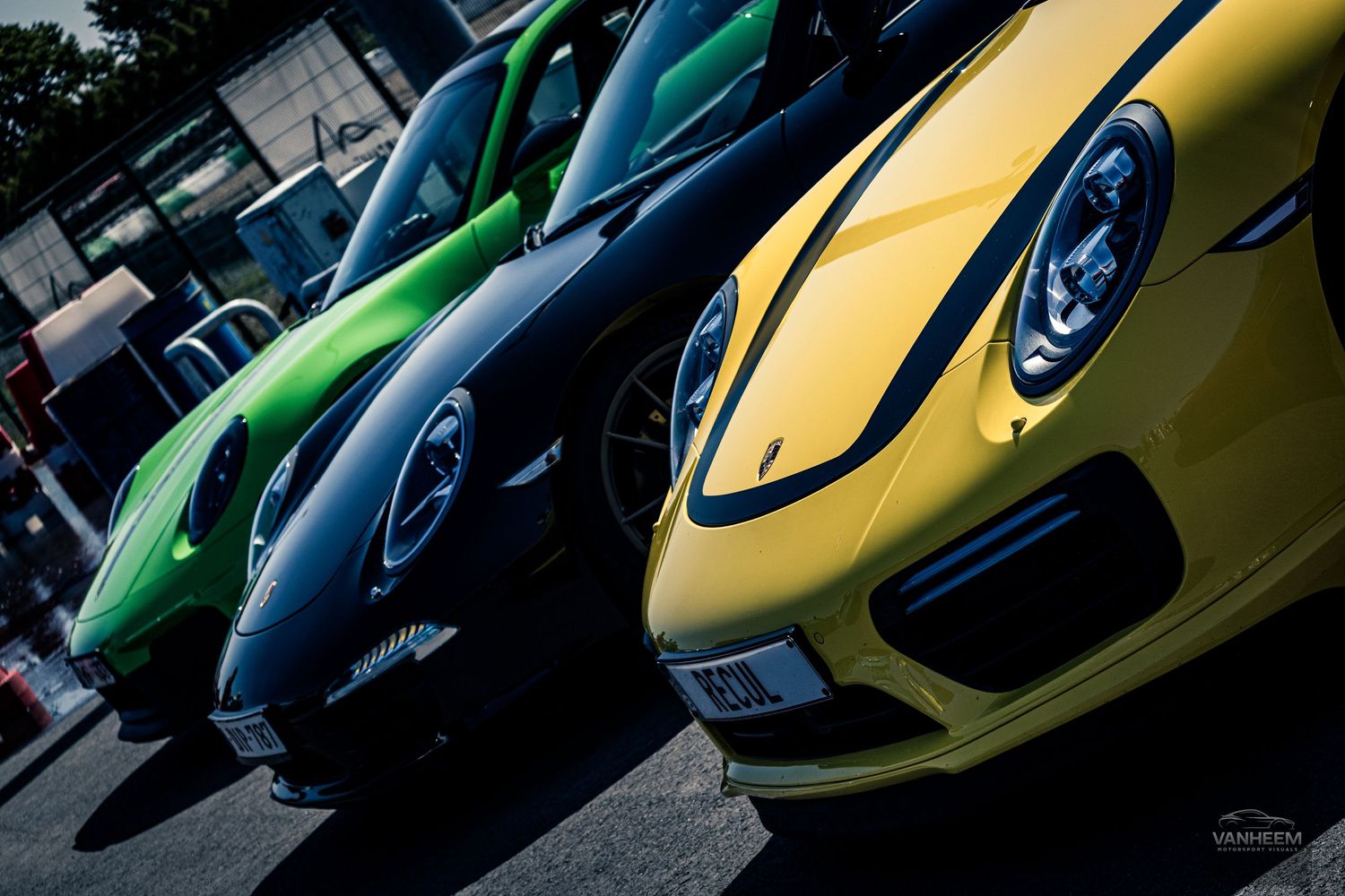 Close-up view of sleek sports cars in green and yellow showcasing their front-end designs at an auto show display.