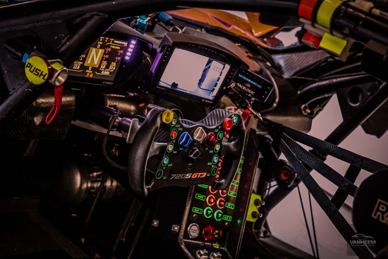 Close-up of a high-tech racing car cockpit featuring a colorful steering wheel with multiple buttons and a digital display.