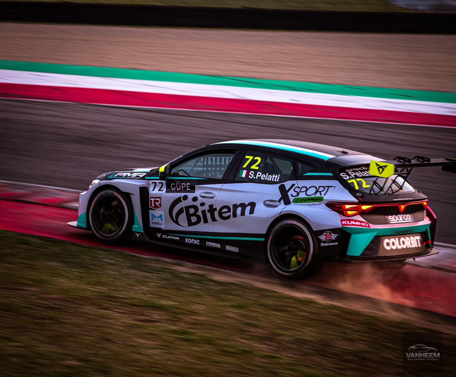 Race cars speed around a track at night with glowing brake rotors and illuminated sponsorship liveries.