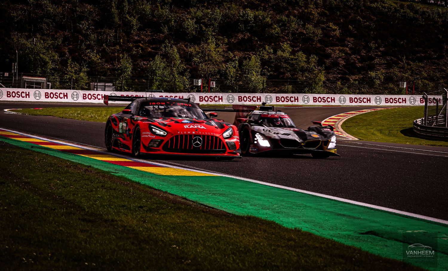 Two racing cars, red Mercedes-AMG and black GT3, battle on track at Spa-Francorchamps with Bosch advertising boards.