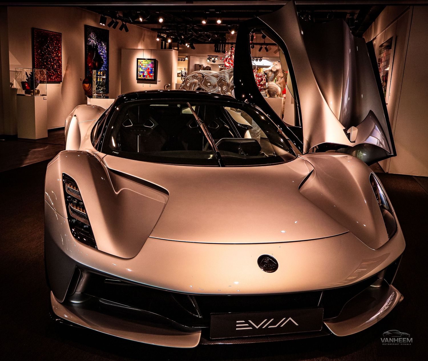 Lotus Evija electric hypercar displayed in a luxury showroom, showcasing its sleek silver aerodynamic design.