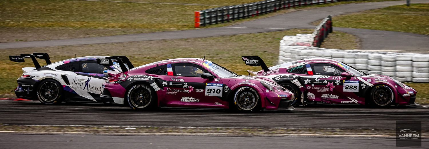 Three pink and white Porsche GT3 race cars competing side by side on a motorsport circuit during a racing event.