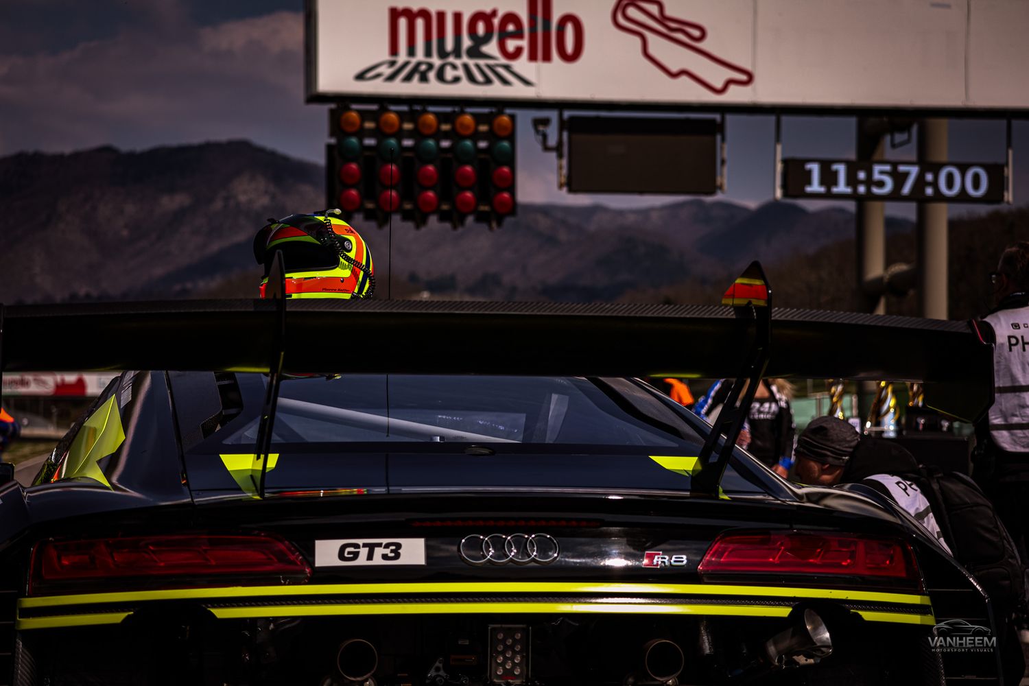 A race car dashboard and display panel at Mugello circuit shown at dusk with timing information visible.