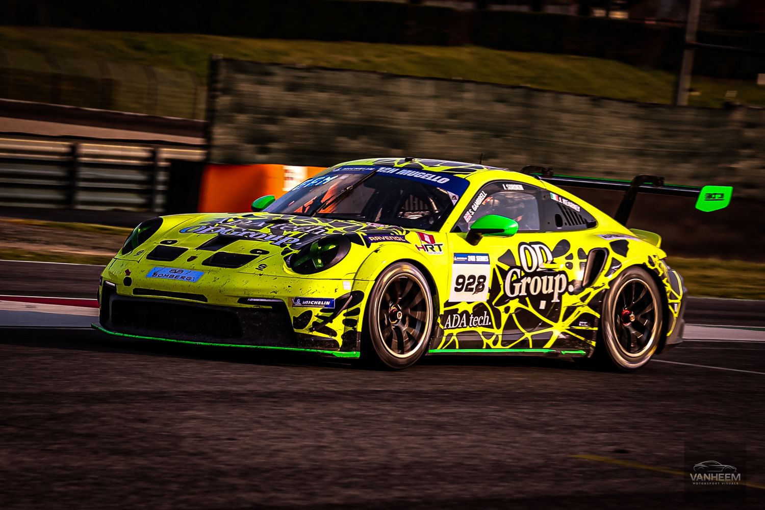 Racing cars speed around a dark racetrack at night with bright neon yellow and green liveries glowing under floodlights.