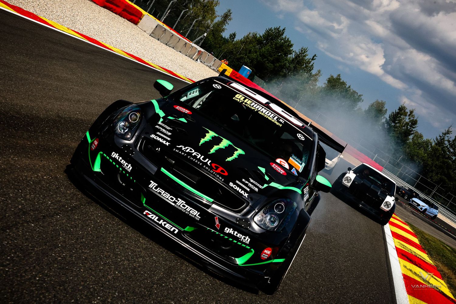 Monster Energy sponsored racing car drifting on a circuit track, with smoke trailing behind on a professional motorsport course.