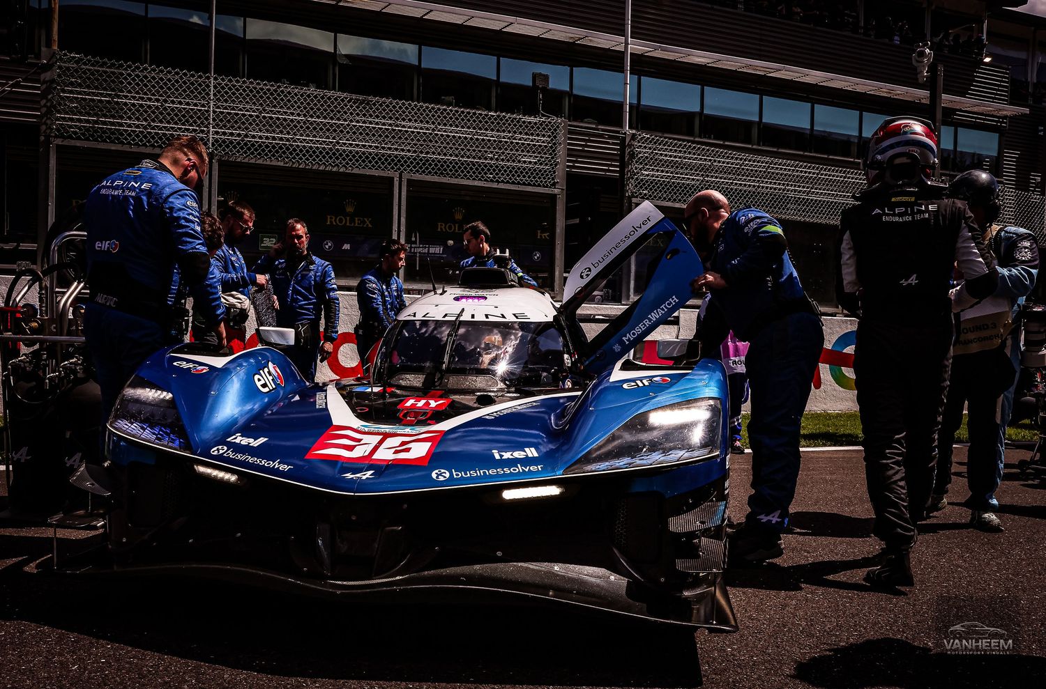 Blue LMP racing car number 31 in pit lane with mechanics working under open hood during nighttime motorsport event.