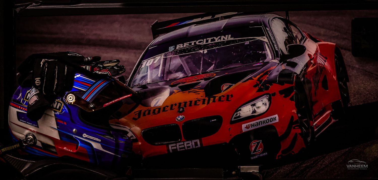 Two racing GT cars, red BMW Z4 with FEBO sponsor and blue car, competing on a dark circuit track.