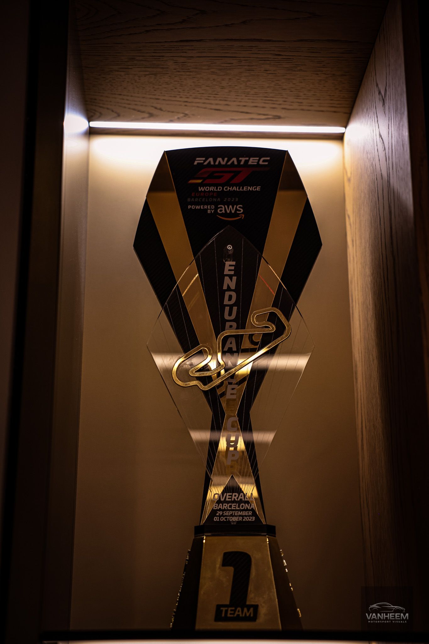 Trophy display case with dramatic lighting showing Ferrari motorsport achievements.
