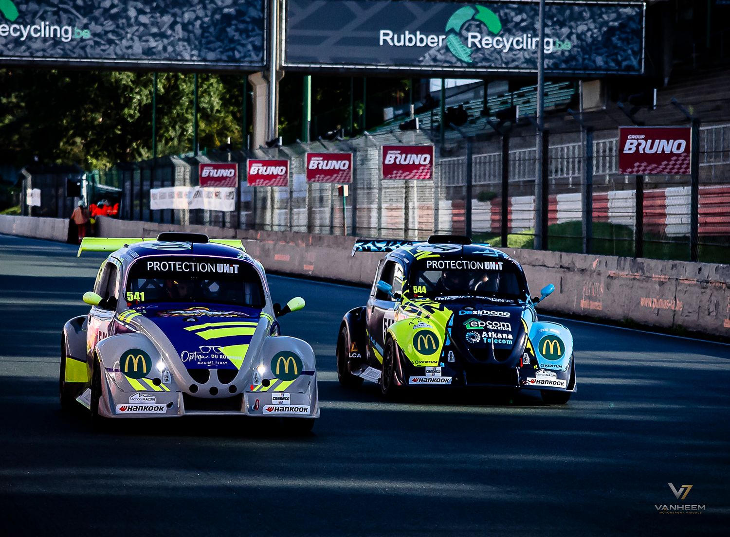 Two McDonald's sponsored racing cars compete on a street circuit track with Rubber Recycling and Bruno advertising boards.