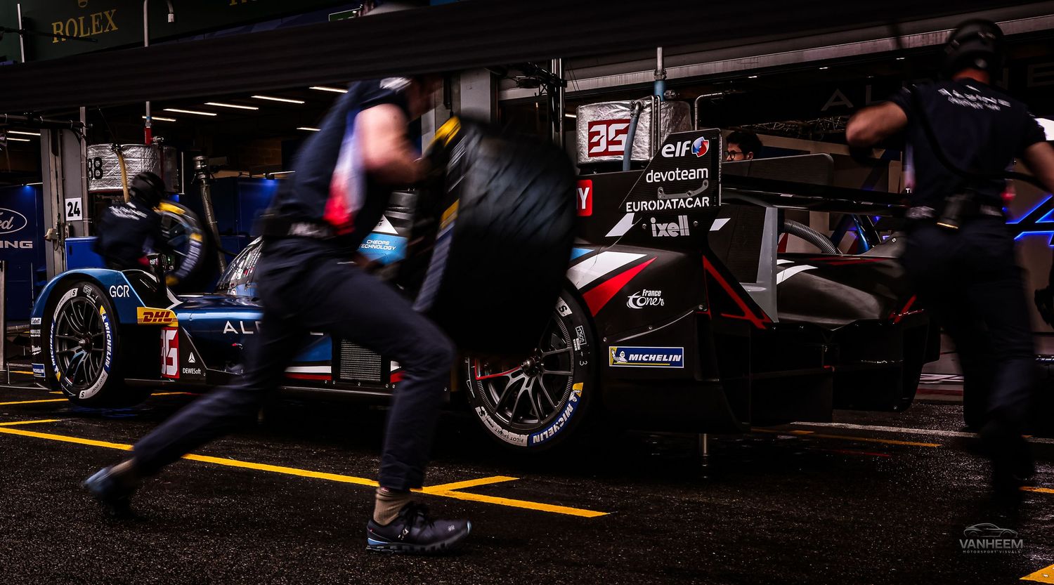 Le Mans pit crew members rush with tires during a nighttime pit stop for car 35 in a motorsport endurance race.