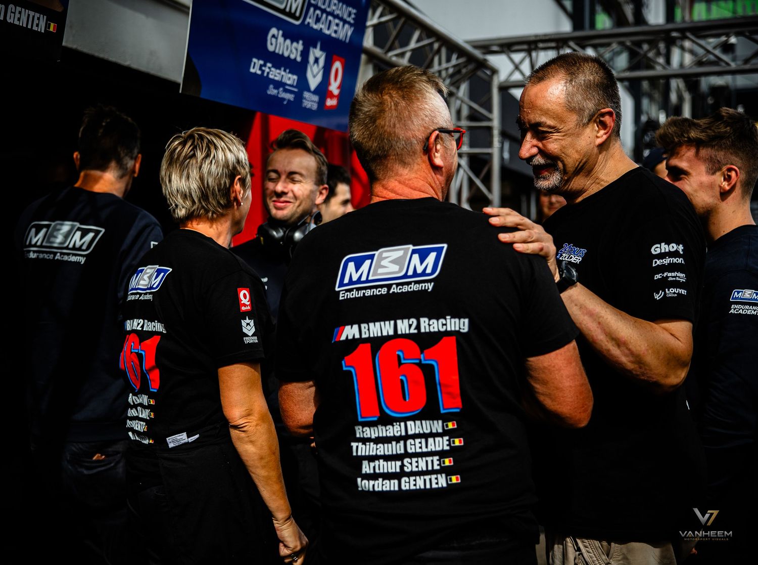 BMW M2 Racing team members in black MOM M2 Racing shirts, number 161, celebrating at a motorsport event.