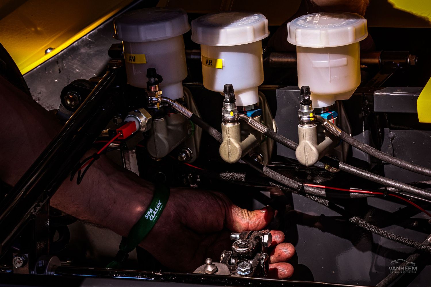 Close-up of a high-performance car engine bay showing master cylinders, fluid reservoirs, and wiring components.