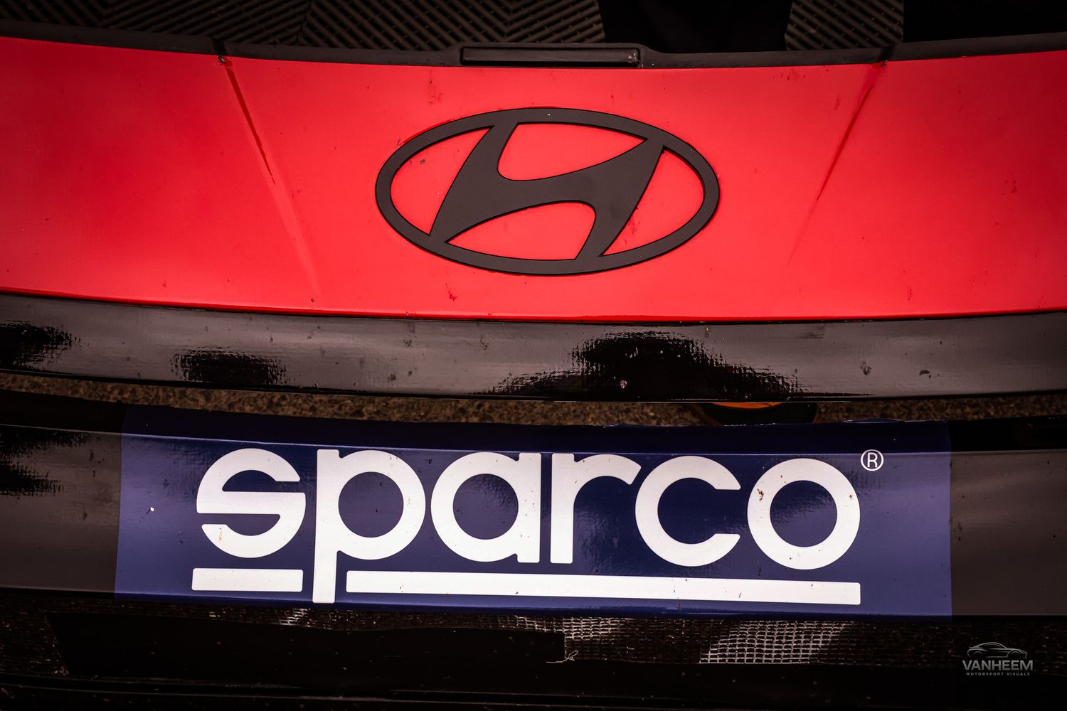 Close-up of a red Hyundai racing car hood featuring the Sparco logo sponsorship decal.