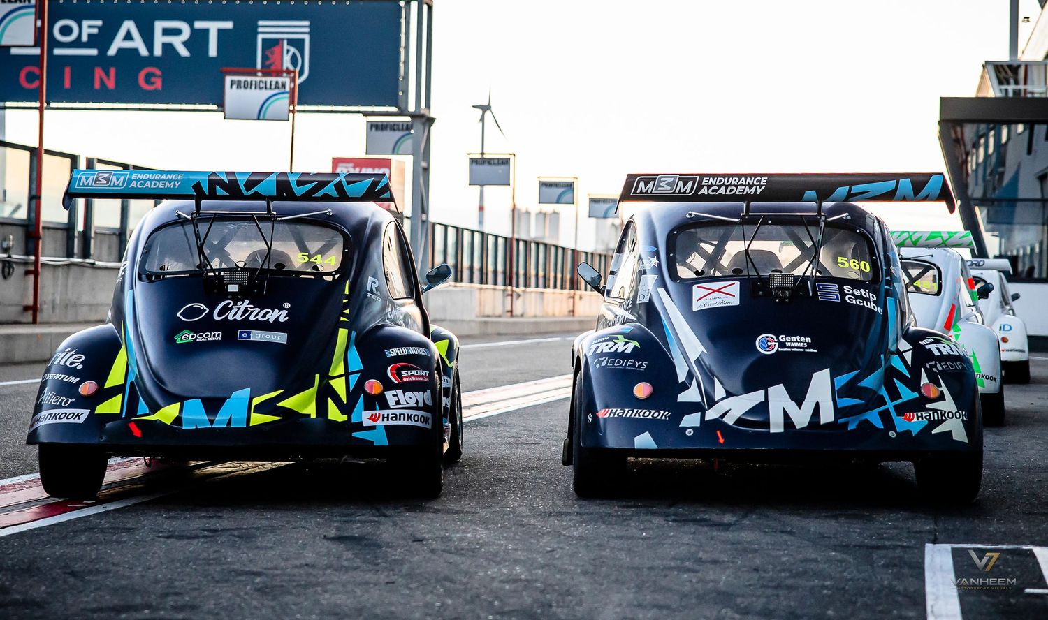 Two Citroen rally cars parked back-to-back in pit lane at a motorsport racing circuit.
