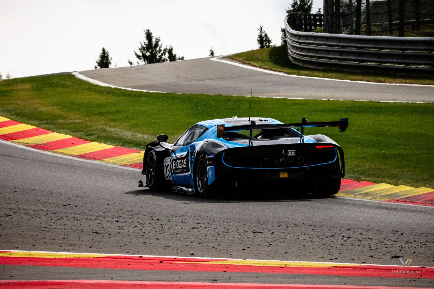 Blue GT racing car navigating a challenging circuit bend at Spa-Francorchamps with a large rear wing visible.