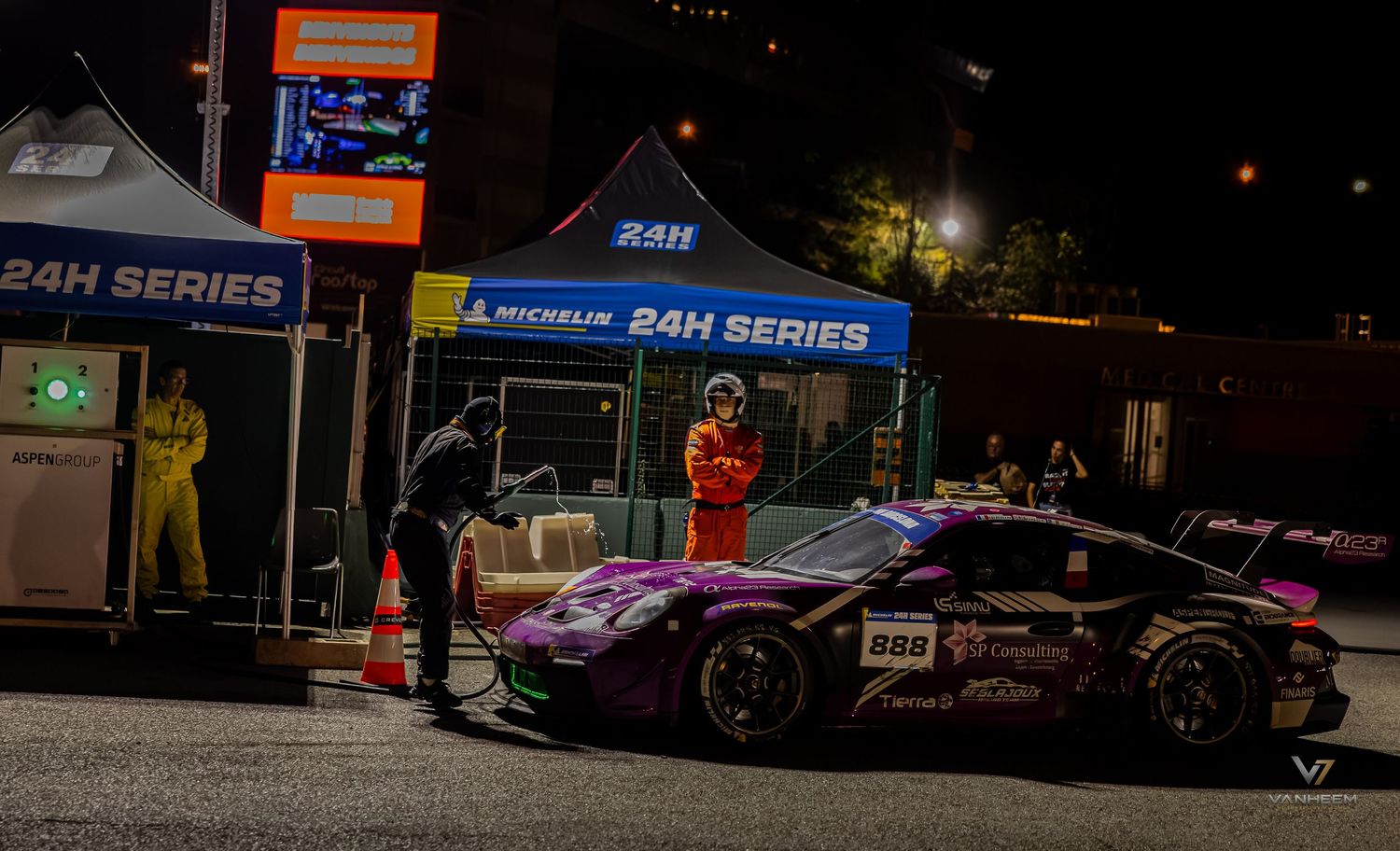 A pink race car at pit stop during 24H Series endurance race at night with crew members and Michelin branding.