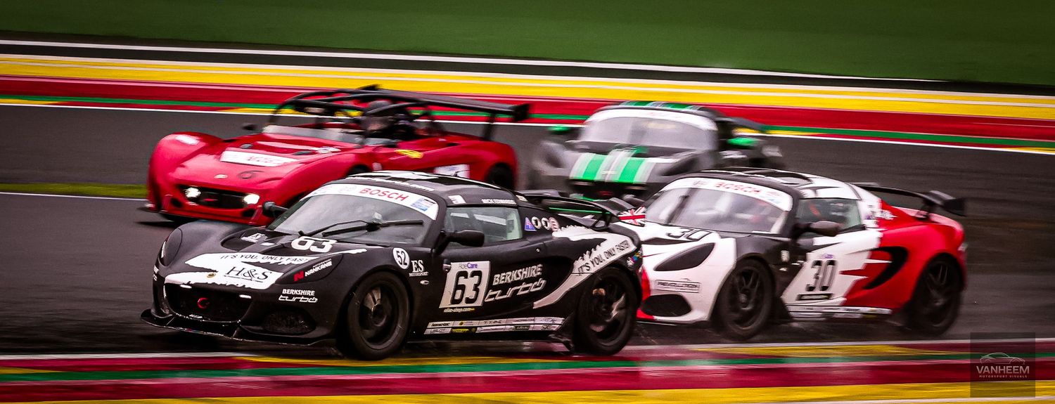 GT racing cars compete on a wet track at Spa-Francorchamps circuit during an intense multi-car race battle.
