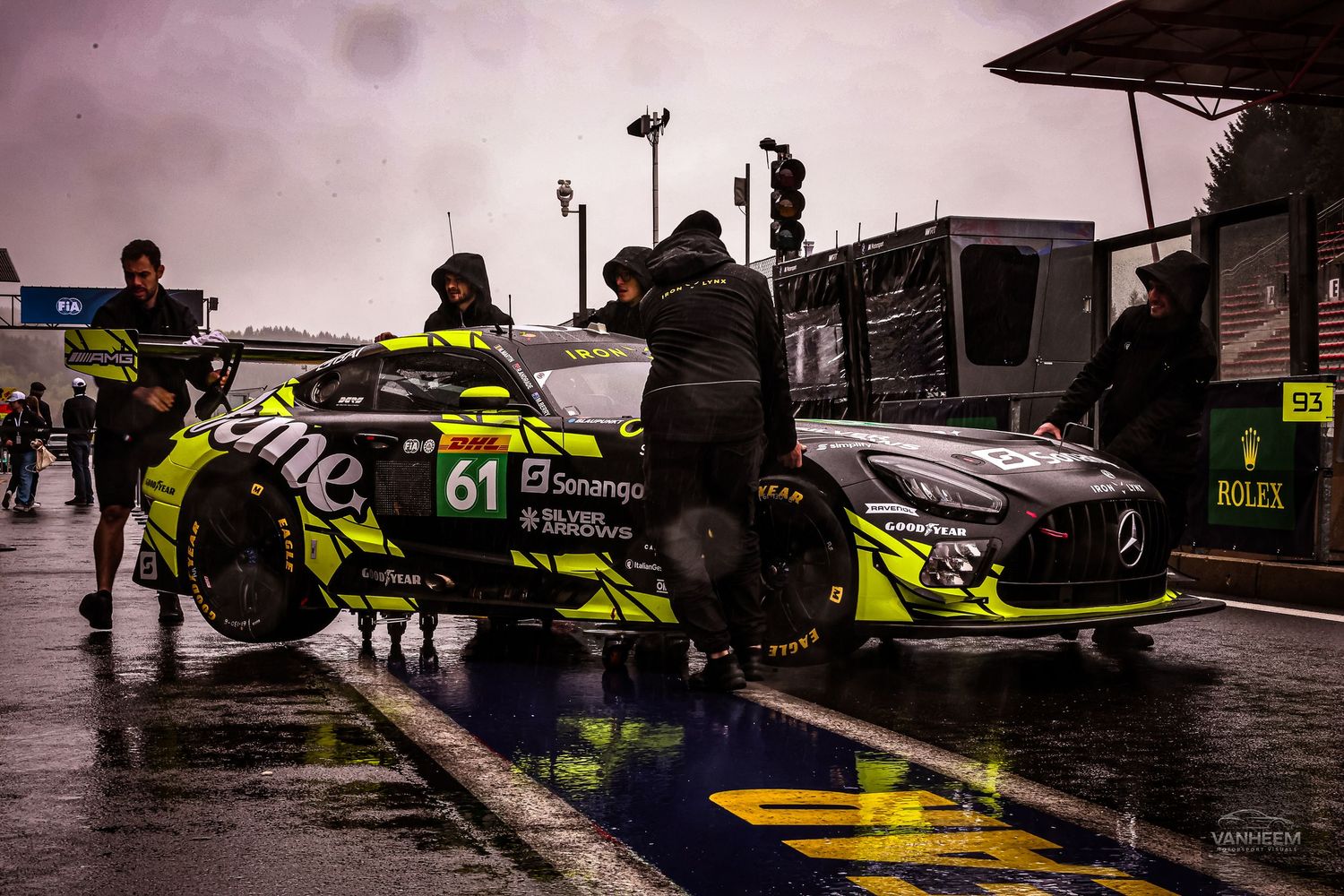 Mercedes-AMG GT3 race car number 61 in pit lane during wet weather conditions at a motorsport racing event.