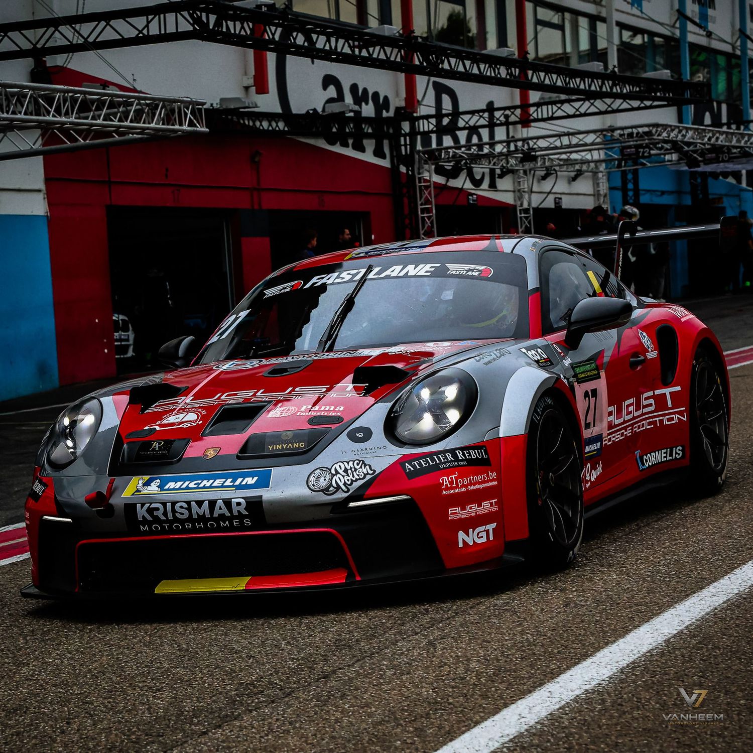 A red and gray Porsche 911 GT3 race car with BST Protection livery parked in pit lane at a motorsport circuit.