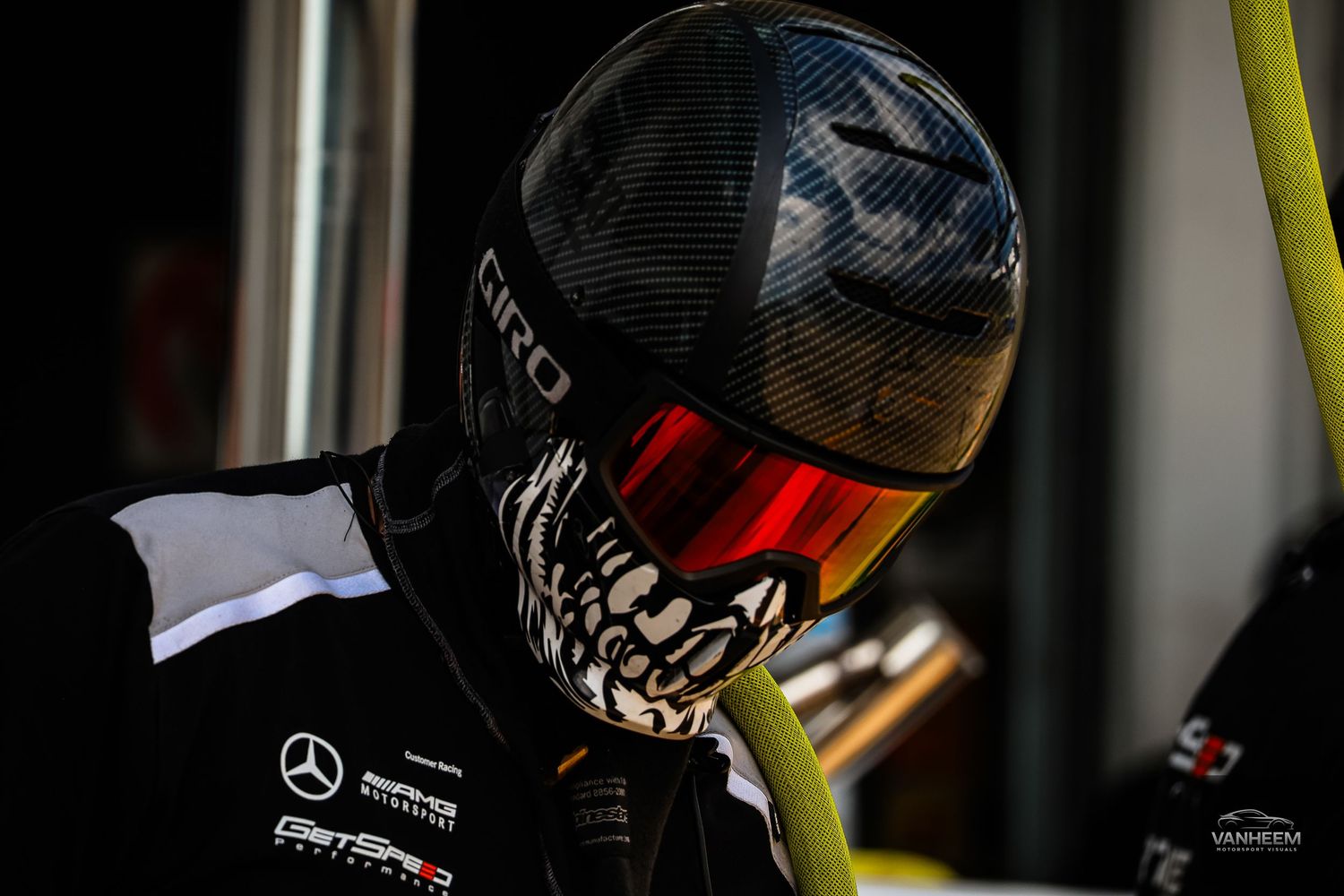 Close-up of a racing driver wearing a Giro helmet with skull design and red visor, Mercedes AMG GT3 team gear.