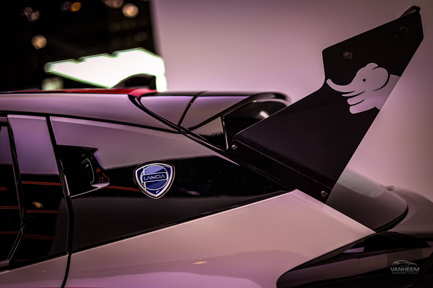 Sleek black Lancia Delta car showcased in dramatic lighting against a dark background with purple accents.
