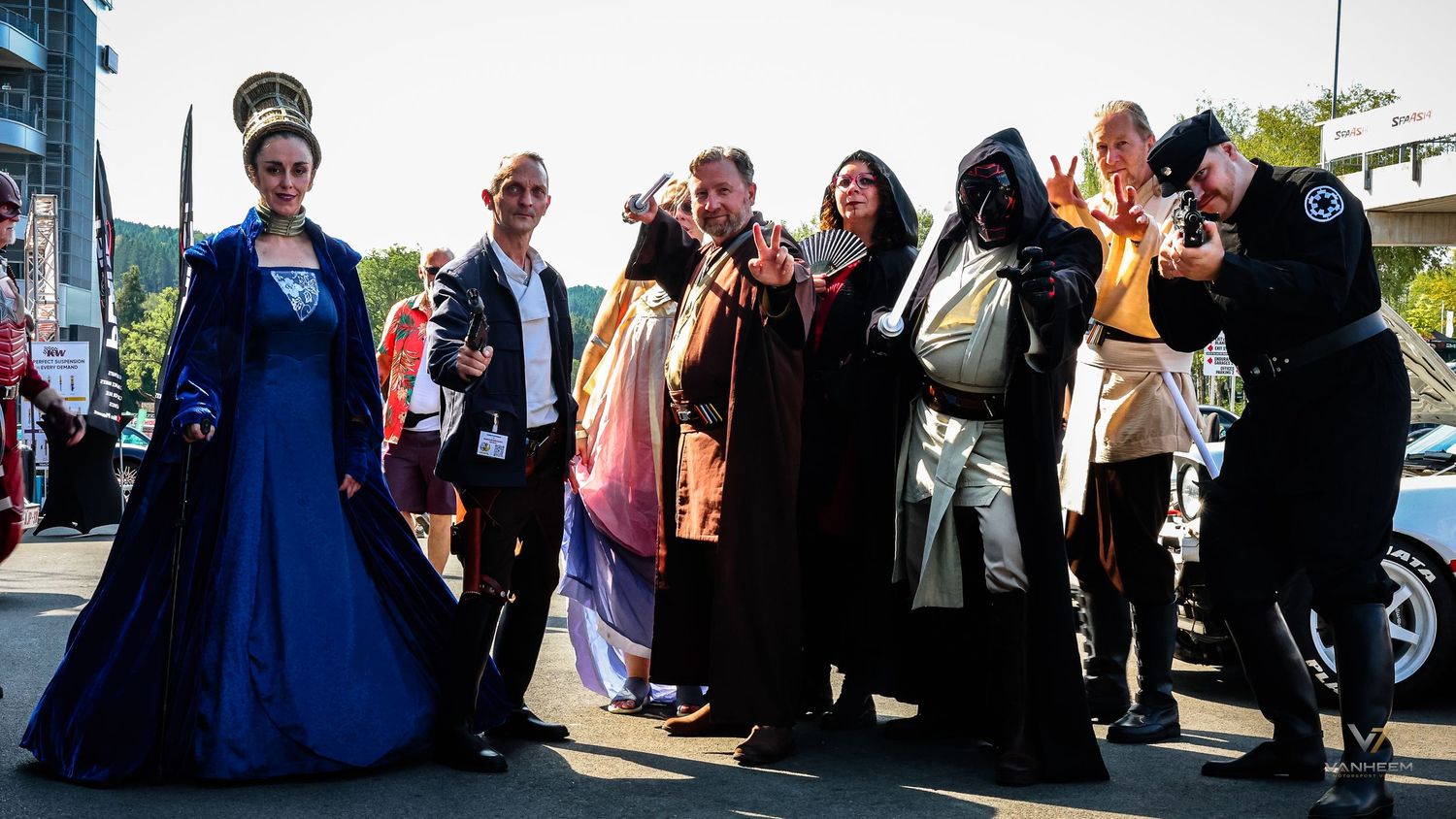 Group of cosplayers in elaborate fantasy and sci-fi costumes posing outdoors at a convention event.