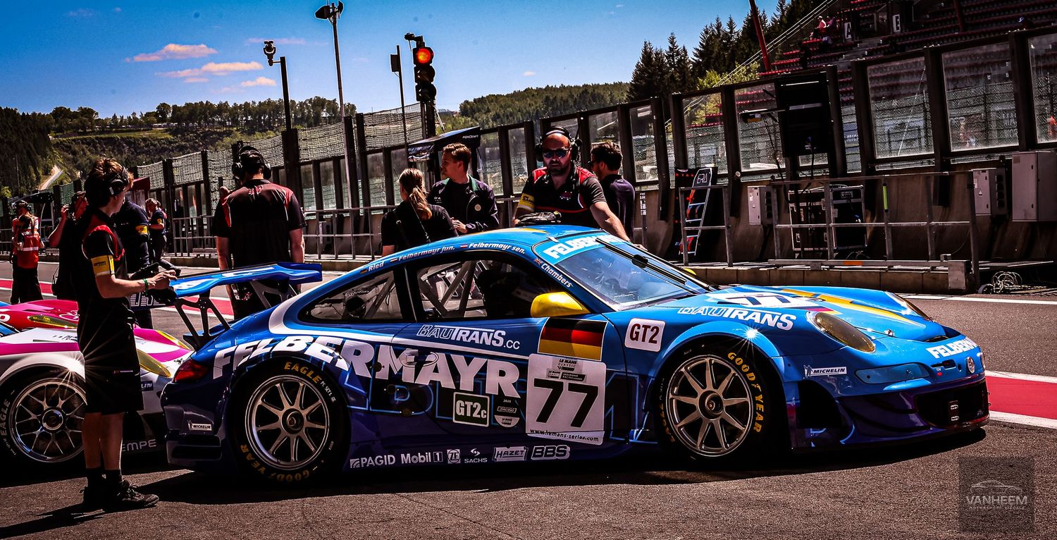Blue Porsche 911 GT3 race car number 77 with MAYR sponsorship in pit lane at motorsport racing event.