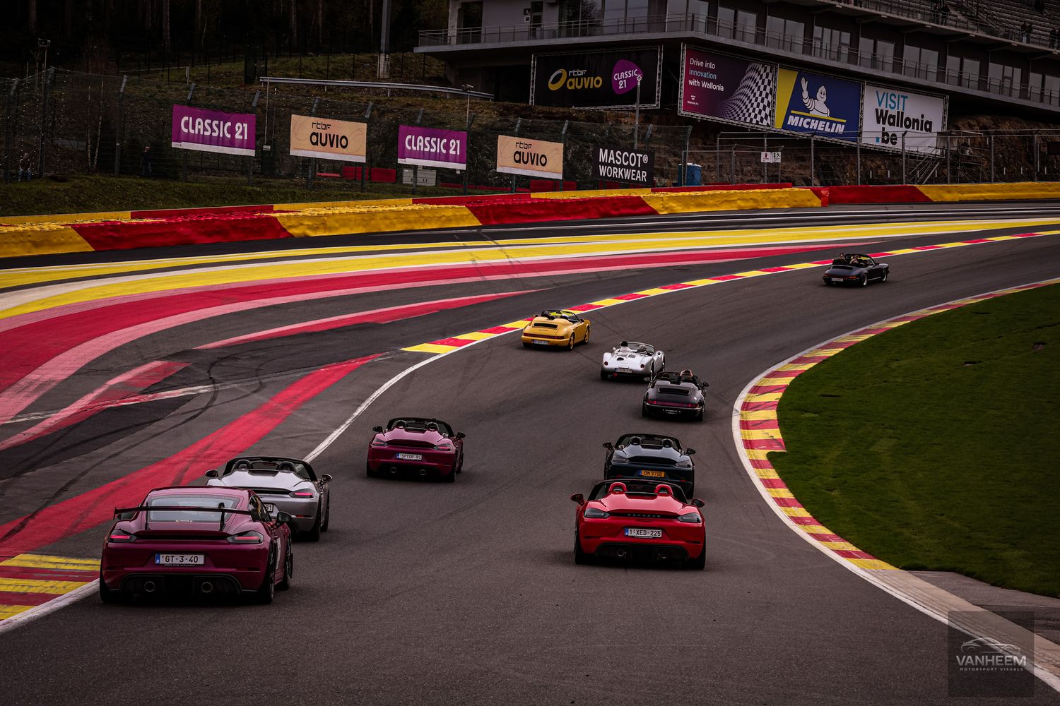 Multiple sports cars racing on the iconic Spa-Francorchamps circuit, navigating the famous Eau Rouge corner.