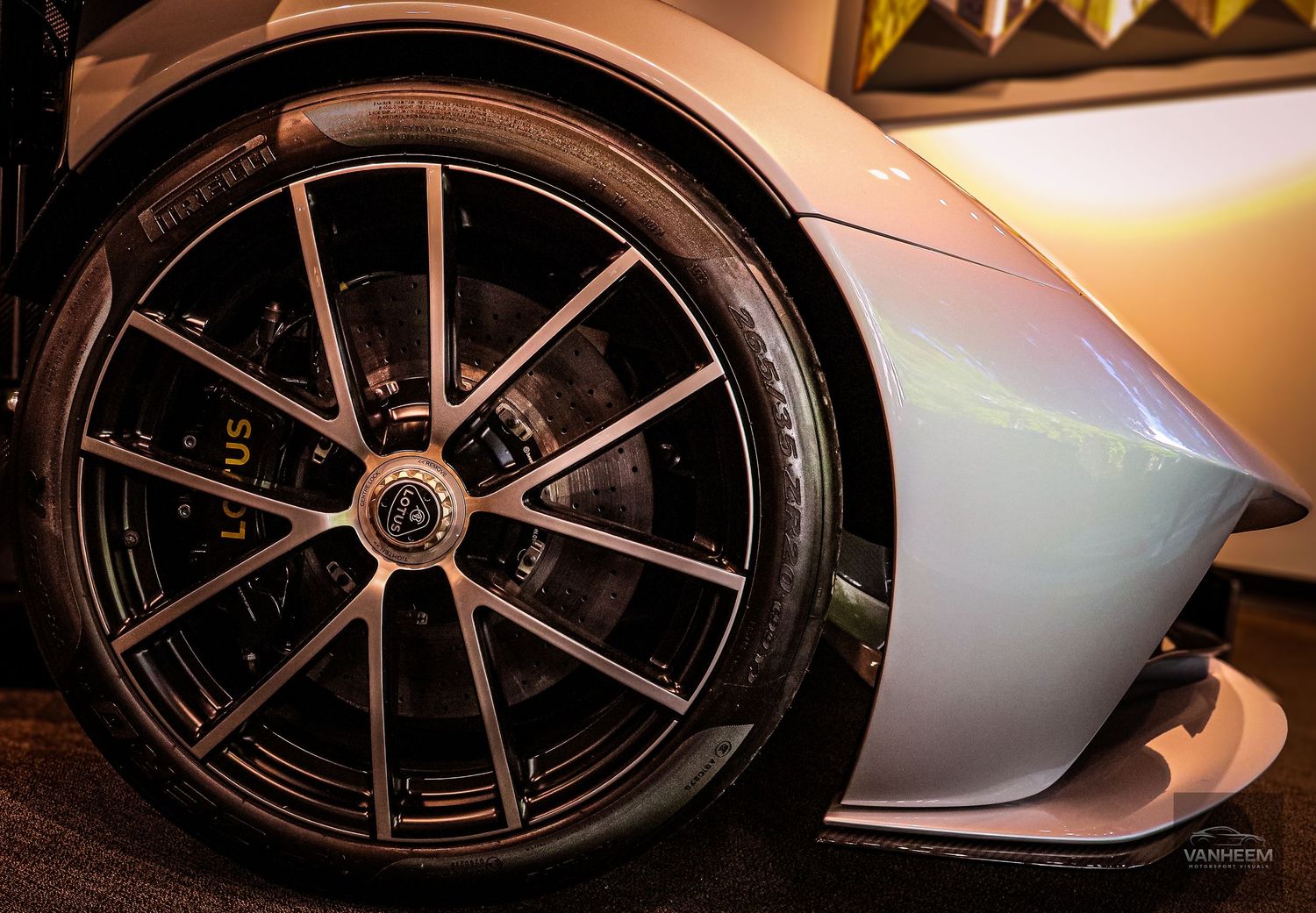 Close-up of a Lotus sports car showcasing a large black multi-spoke alloy wheel with performance brake caliper.