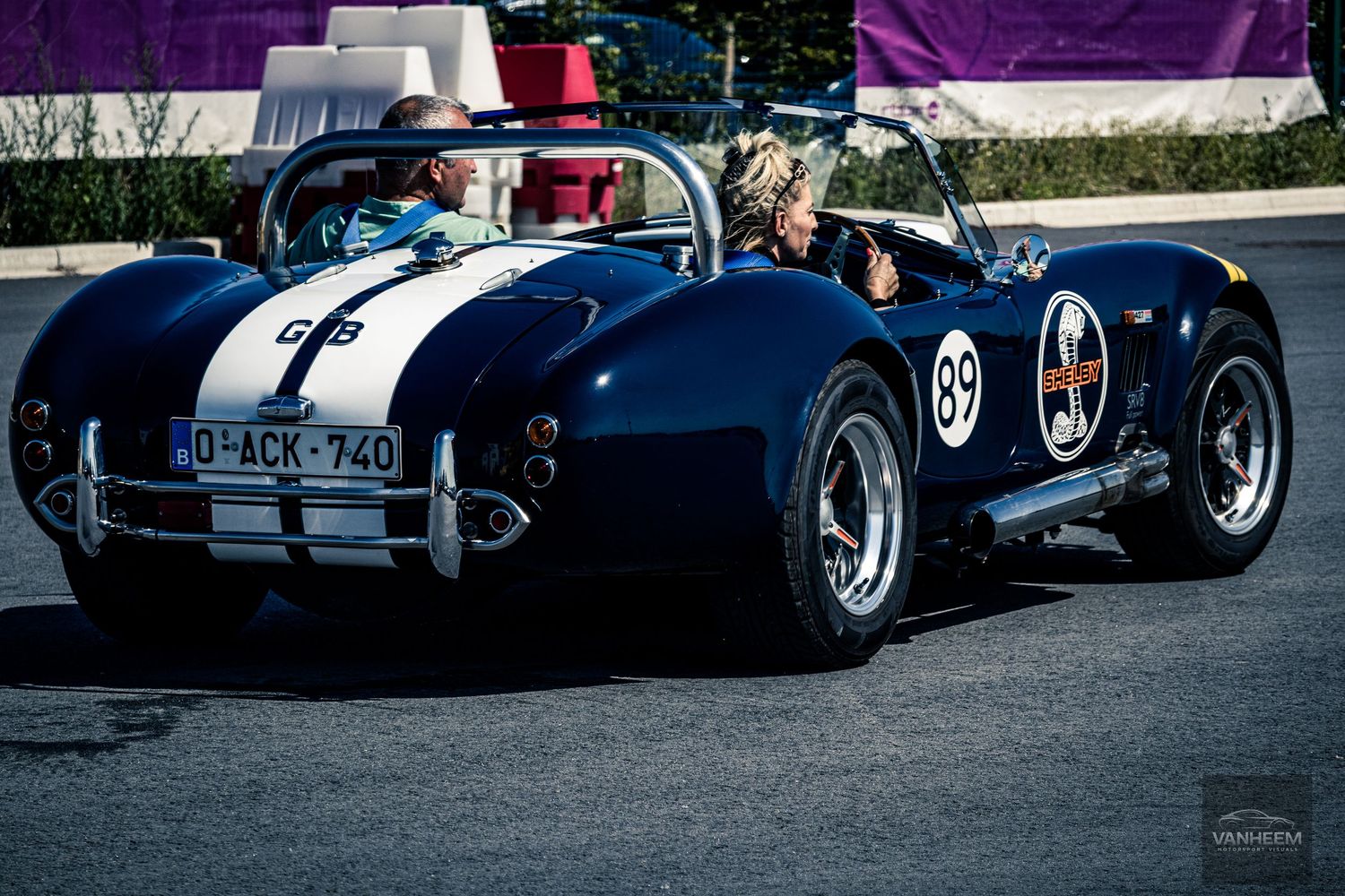 A collection of vintage Shelby Cobra sports cars lined up at a car show displaying their iconic blue and chrome finishes.